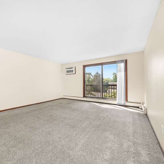 a room with a grey carpet and a window overlooking a balcony.