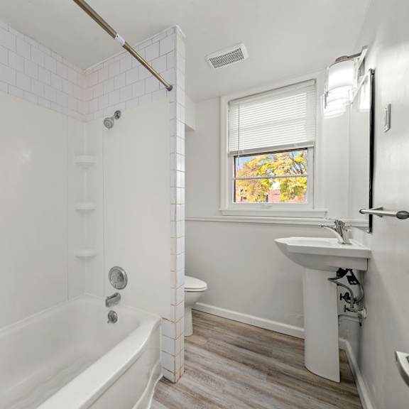 a white bathroom with a tub, sink, and toilet.
