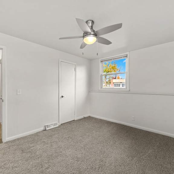 a room with a ceiling fan and a window with a view of a garden.