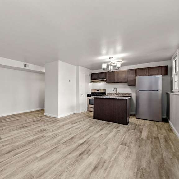 a kitchen area with a refrigerator, sink, and cabinets.