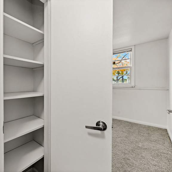 a white closet with shelves and a door.