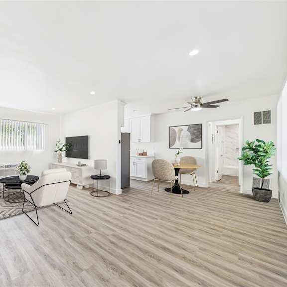 a living room with a white couch, a television, and a ceiling fan.