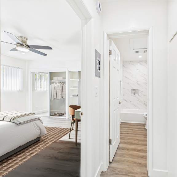 a bedroom with a bed, chair, and a fan.