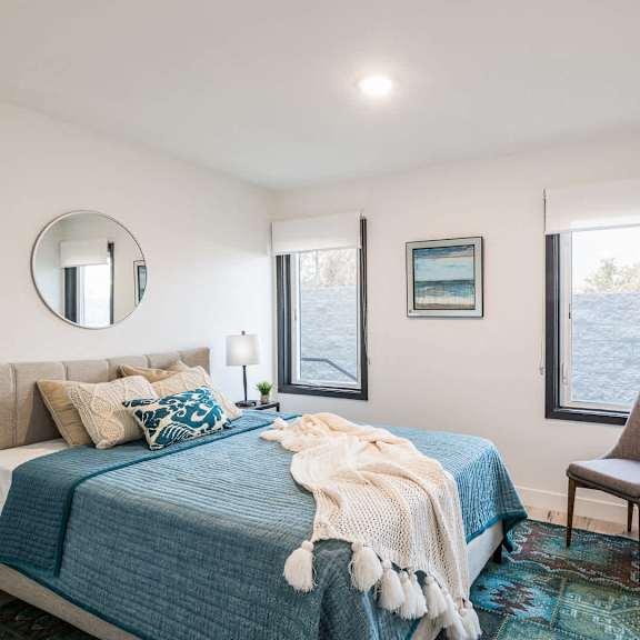 a bedroom with a bed, a chair, and a window overlooking a body of water.