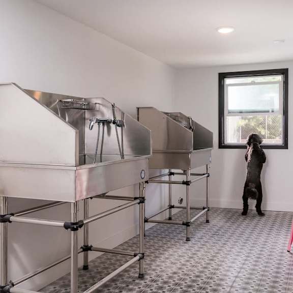 a person stands in a room with a large stainless steel machine and a pink chair.