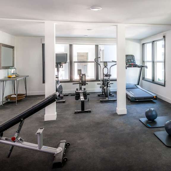 a spacious gym with a variety of equipment including a treadmill, a rowing machine, and a bench press.