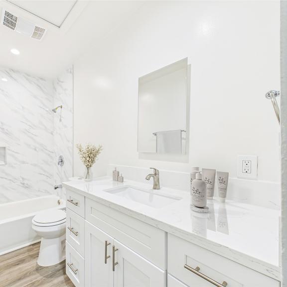 a white bathroom with a marble wall and a toilet.