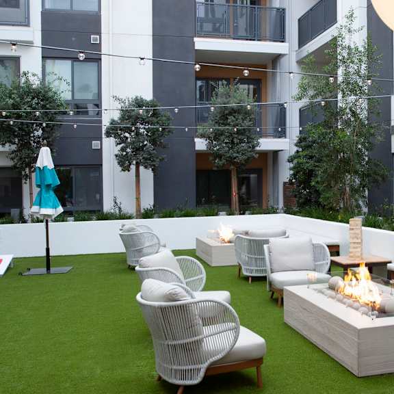 a modern outdoor seating area with white furniture and a fire pit.