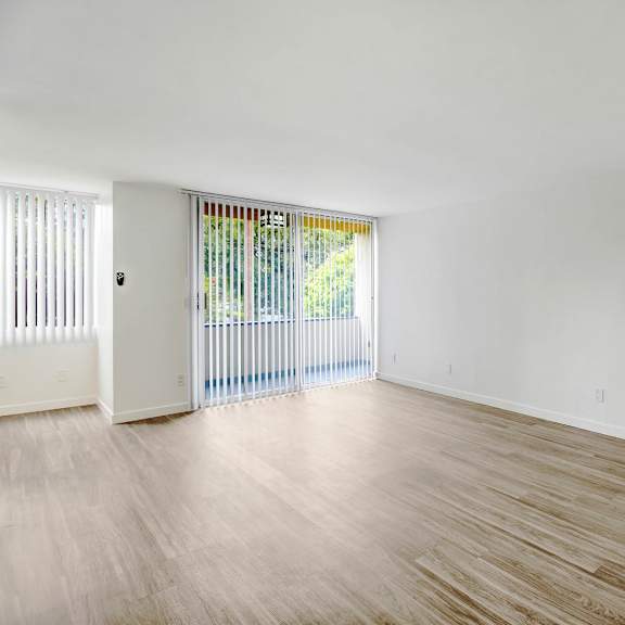 the living room and dining room of an empty house with wood floors and white walls
