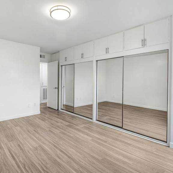 an empty room with white walls and mirrored closet doors