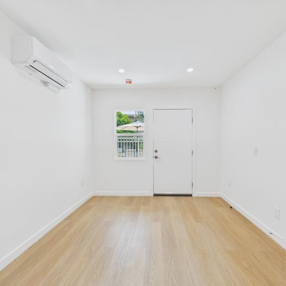 a room with a white door and a window showing greenery outside.