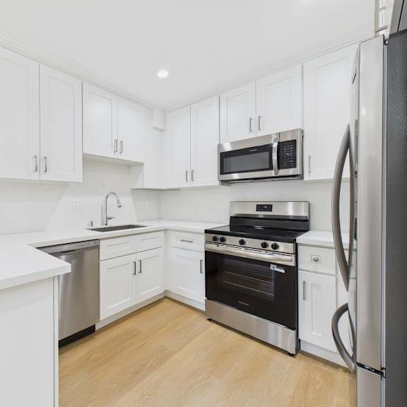 a kitchen with white cabinets and stainless steel appliances.