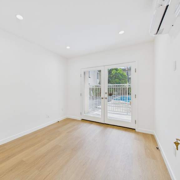 a room with a wooden floor and a sliding glass door leading to a balcony.
