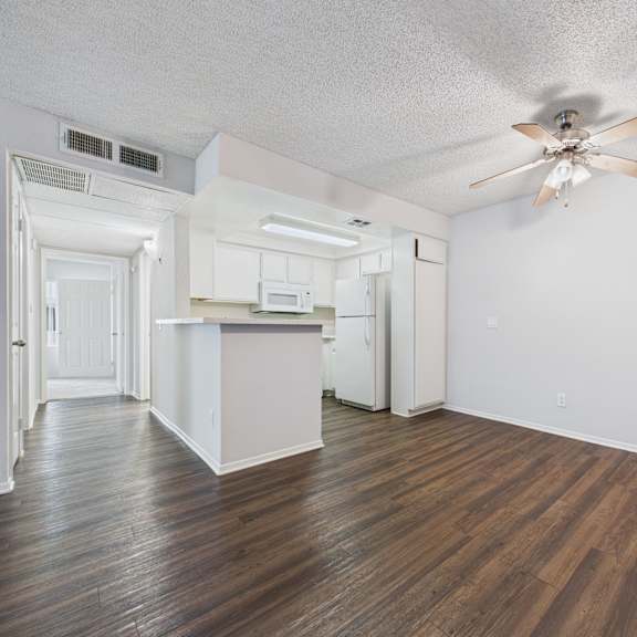 a room with a ceiling fan and wooden flooring.