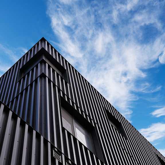 a modern building with a black facade and a blue sky in the background.