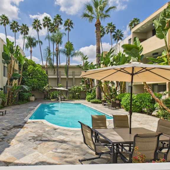 a pool surrounded by chairs and trees.