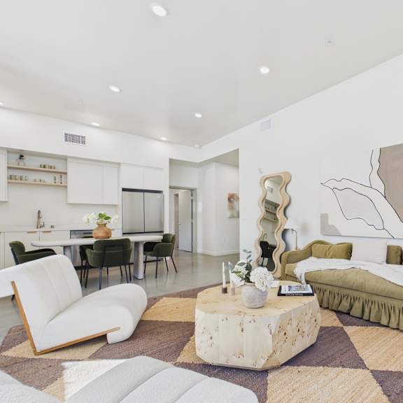 a living room with a white chair, a green sofa, and a rug with a checkered pattern.