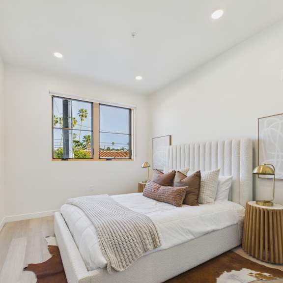 a bedroom with a large bed and a window with a view of trees.