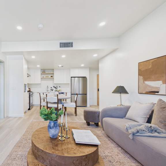 a modern living room with a round mirror and a coffee table with a vase of flowers on it.