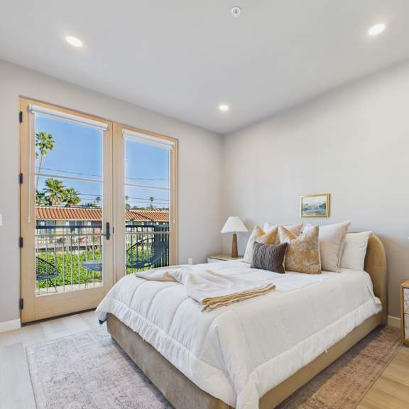 a bedroom with a large bed and a view of a patio through a sliding glass door.