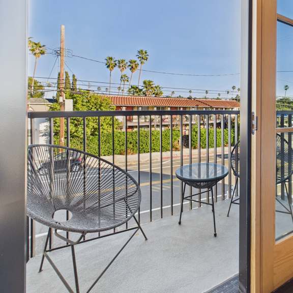 a balcony with a table and chairs overlooking a street.