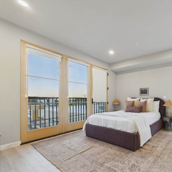 a bedroom with a large bed and a view of the ocean through the sliding glass doors.