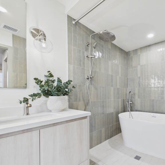 a white bathroom with a white tub and a plant on the sink.