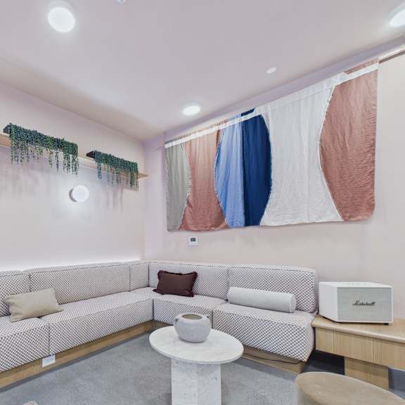 a living room with a grey sofa, a white coffee table, and a large abstract painting on the wall.