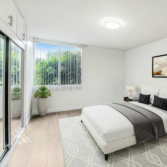 a white bedroom with a bed and a sliding glass door