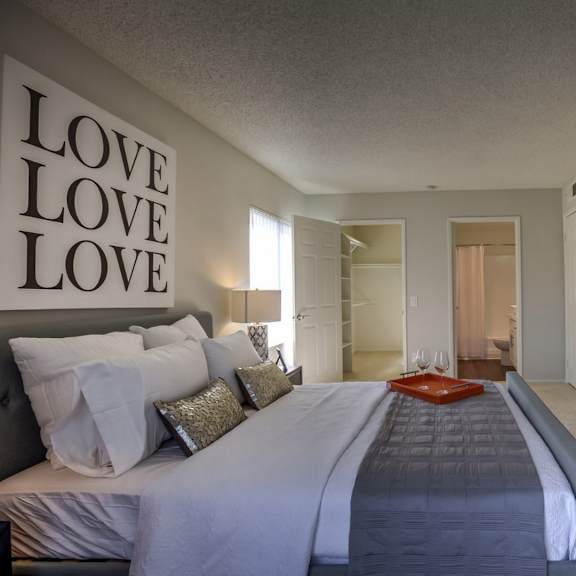 a bedroom with a large bed and a wall decorated with the word "love" in large letters.