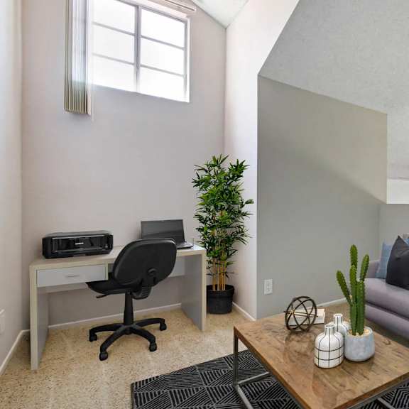 a living room with a grey couch, a black chair, a wooden coffee table, and a plant.