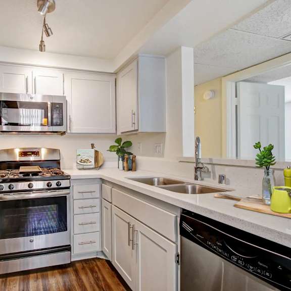 a modern kitchen with stainless steel appliances and wooden floors.