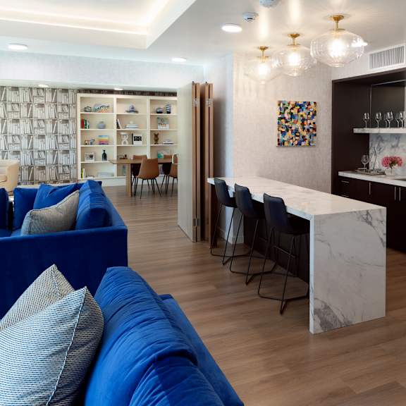 a modern living room with a blue sofa and a kitchen area in the background.