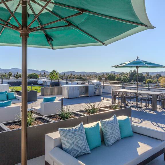 a patio with a white couch and a green umbrella.