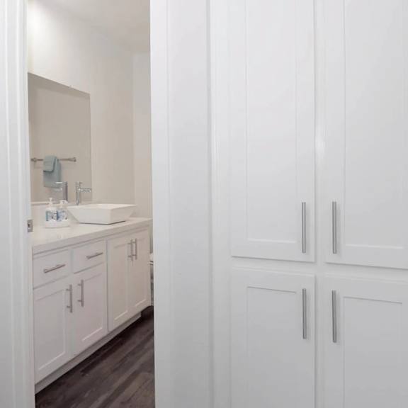 a white bathroom with a sink and cabinets.