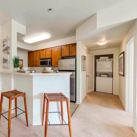 a kitchen with a white countertop and wooden stools.