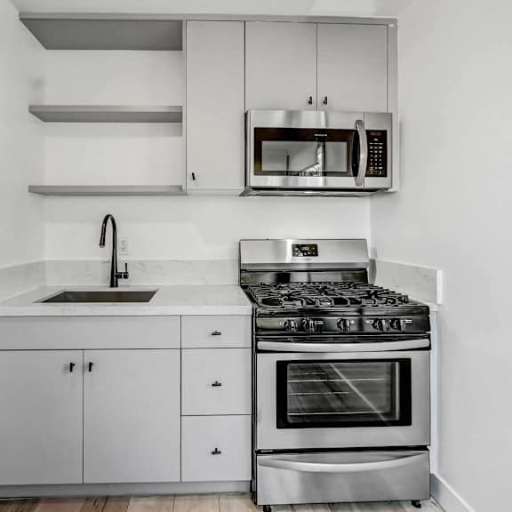 a modern kitchen with a stove, sink, and cabinets.