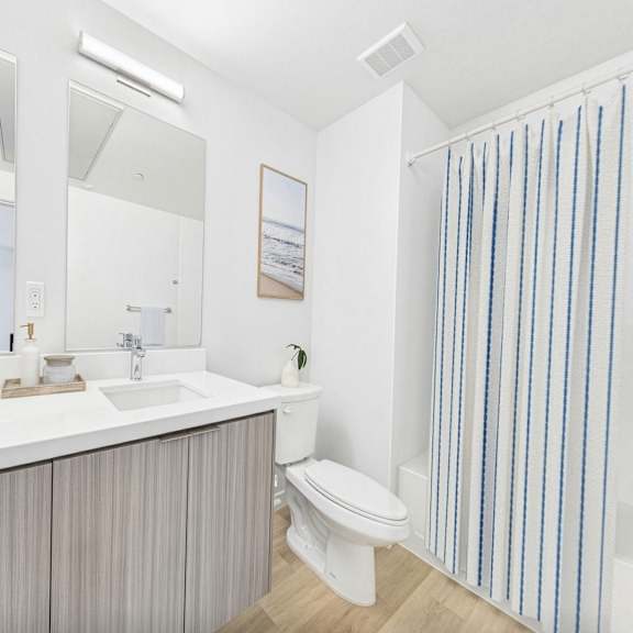 a bathroom with a white countertop and striped shower curtain.