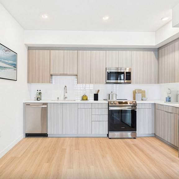 a modern kitchen with stainless steel appliances and wooden flooring.