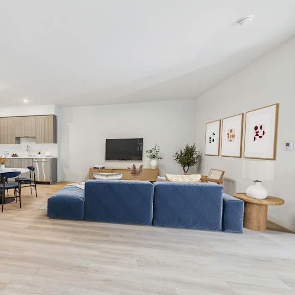 a modern living room with a blue sofa and a dining table with chairs.