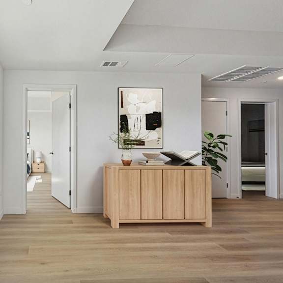 a room with a wooden floor and a wooden cabinet with a vase on top.