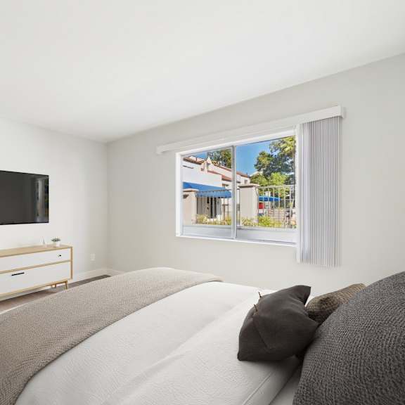 a bedroom with a bed, a dresser, and a window with a view of a street.