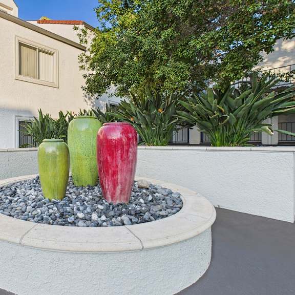 a fountain with three apples in different colors is in the foreground.