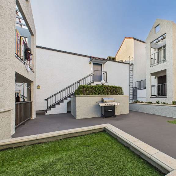 a courtyard with a small garden and a white building with a balcony.