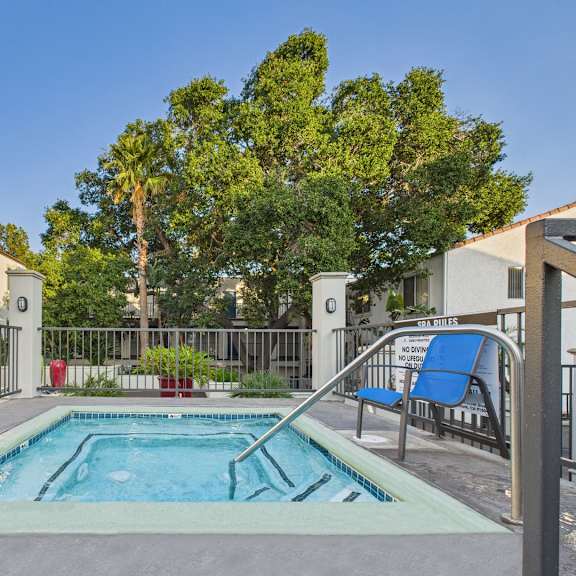 a small pool surrounded by a fence and chairs.