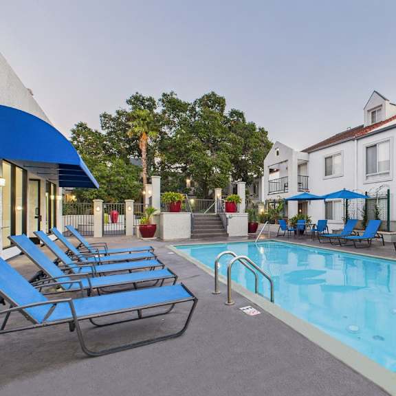 a pool surrounded by lounge chairs and umbrellas.