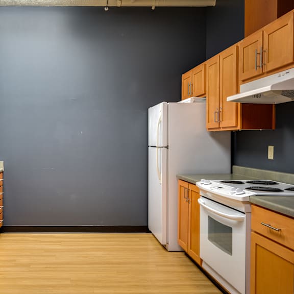 an empty kitchen with wooden cabinets and a white refrigerator
