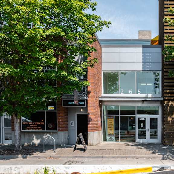 a brick building with glass windows and a tree on the sidewalk
