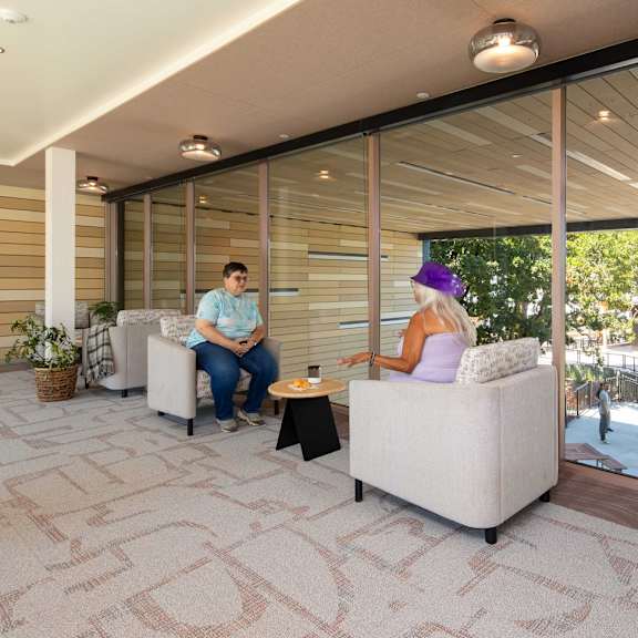 two people sitting on a couch in a room with a tiled floor.