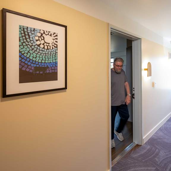 a man is standing in a hallway with a framed picture on the wall.